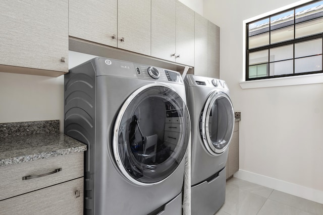 laundry room featuring washer and clothes dryer, cabinets, and light tile patterned floors