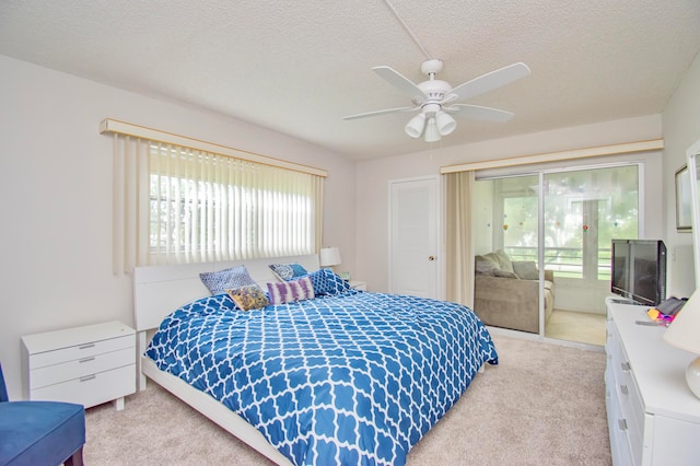 carpeted bedroom featuring access to outside, a textured ceiling, multiple windows, and ceiling fan