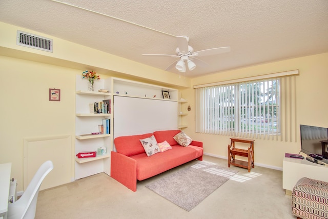 carpeted living room with ceiling fan and a textured ceiling