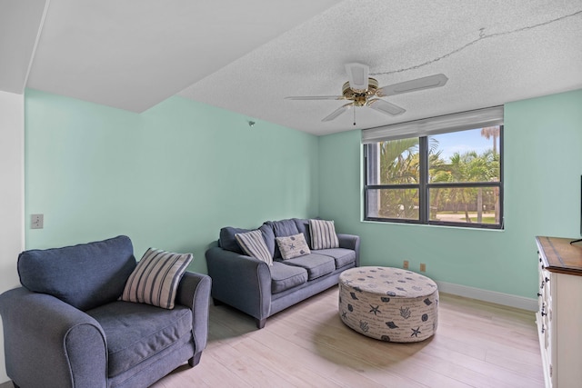 living room with ceiling fan, a textured ceiling, and light wood-type flooring