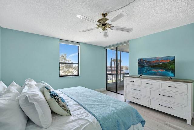 bedroom featuring ceiling fan, access to exterior, a textured ceiling, and multiple windows