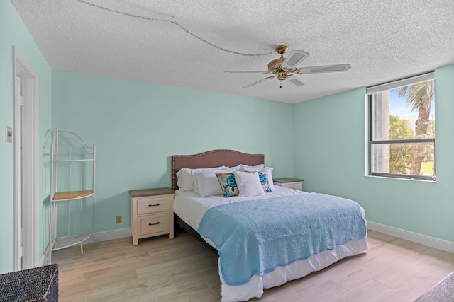 bedroom with a textured ceiling, light hardwood / wood-style flooring, and ceiling fan