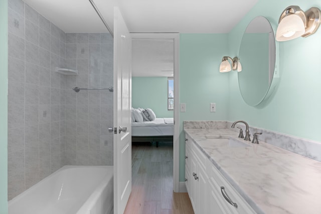 bathroom with vanity, wood-type flooring, and tiled shower / bath combo