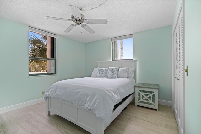 bedroom with a textured ceiling, a closet, ceiling fan, and light hardwood / wood-style floors