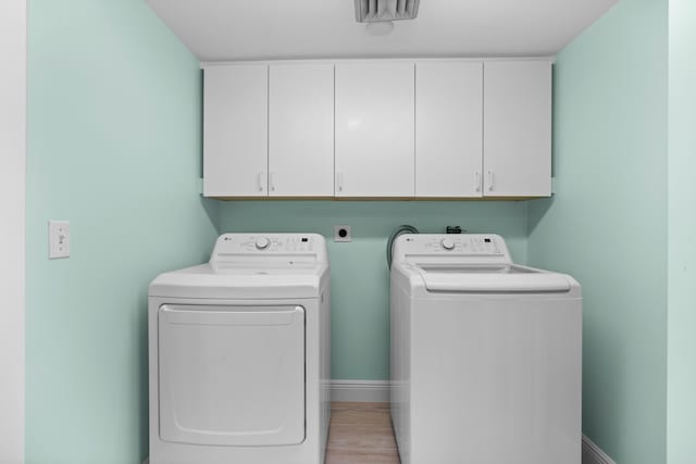 clothes washing area with cabinets and independent washer and dryer