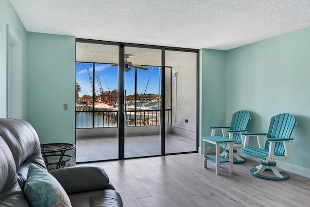 sitting room featuring ceiling fan, a water view, a textured ceiling, and hardwood / wood-style flooring