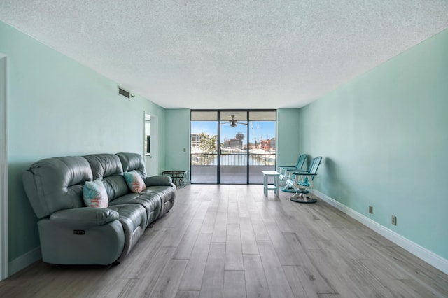 living room with a textured ceiling, light hardwood / wood-style floors, and floor to ceiling windows