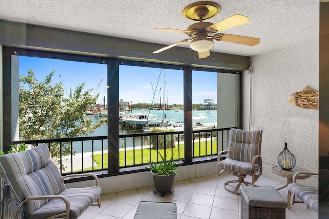 sunroom / solarium featuring ceiling fan and a water view