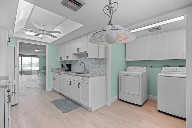 clothes washing area with ceiling fan, sink, cabinets, light hardwood / wood-style floors, and washer and dryer