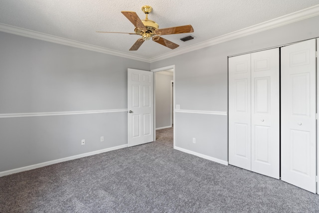 unfurnished bedroom with ceiling fan, a closet, a textured ceiling, and dark colored carpet