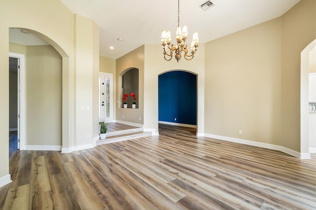 empty room featuring a chandelier and light hardwood / wood-style floors