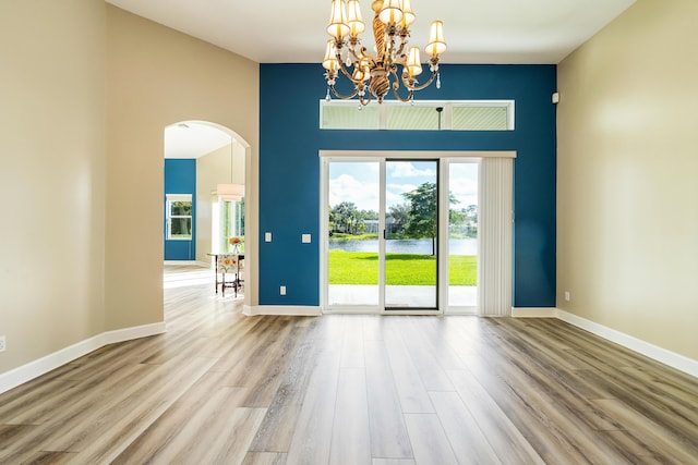 spare room featuring hardwood / wood-style floors, a high ceiling, and a notable chandelier