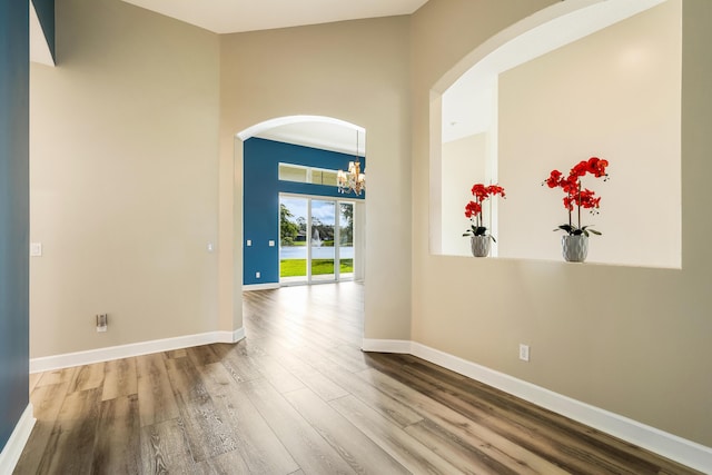 empty room with hardwood / wood-style floors and a notable chandelier