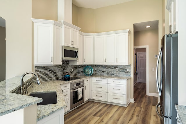 kitchen featuring white cabinets, appliances with stainless steel finishes, light stone countertops, and sink