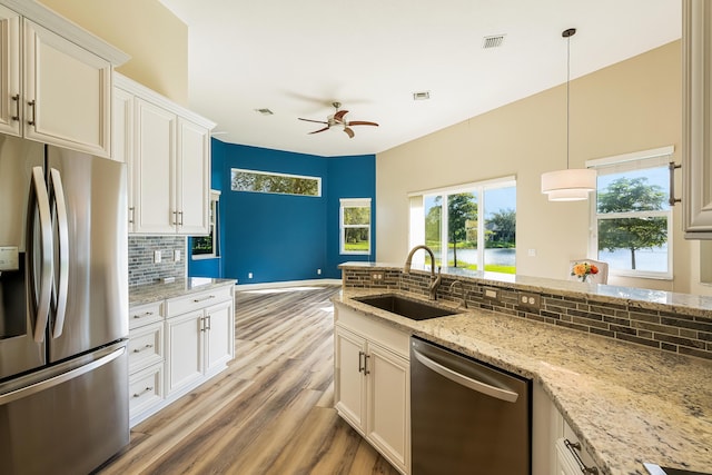 kitchen with sink, appliances with stainless steel finishes, tasteful backsplash, decorative light fixtures, and white cabinetry