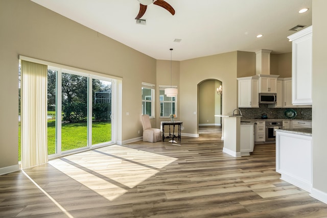 kitchen featuring backsplash, light stone countertops, decorative light fixtures, white cabinetry, and stainless steel appliances