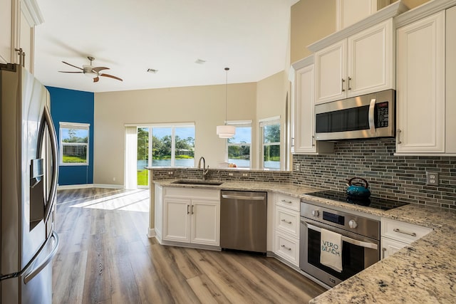 kitchen with white cabinets, light stone counters, sink, and stainless steel appliances