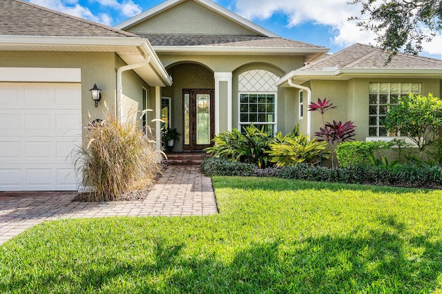 entrance to property featuring a lawn and a garage