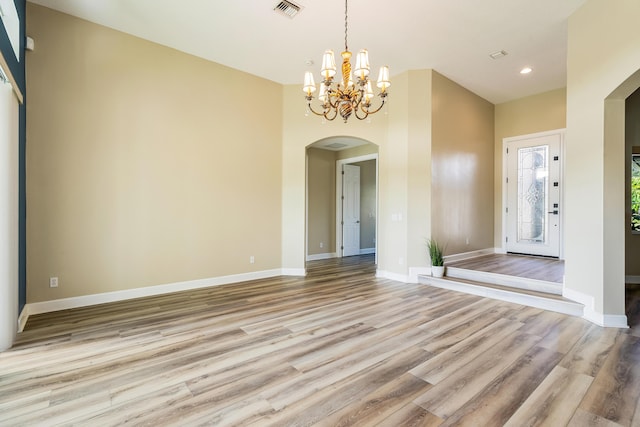 spare room featuring a notable chandelier and light hardwood / wood-style flooring