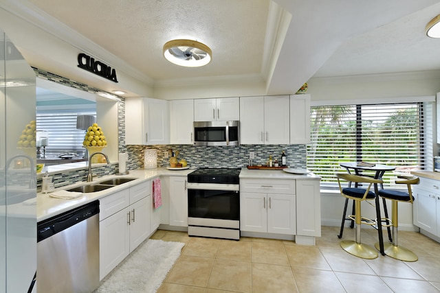 kitchen with light tile patterned floors, white cabinets, stainless steel appliances, and sink