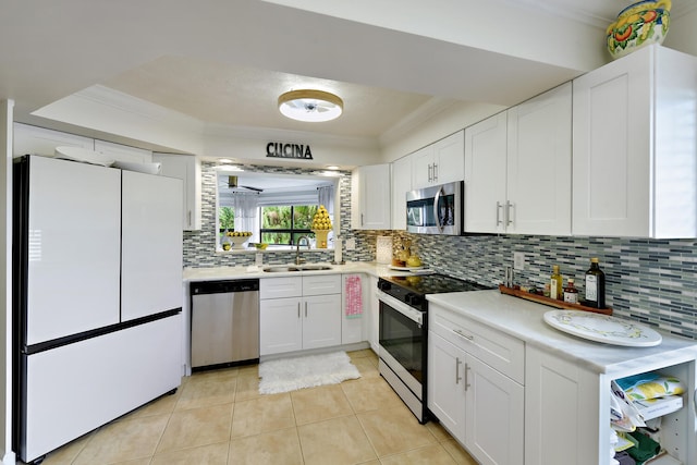 kitchen with white cabinets, ornamental molding, sink, appliances with stainless steel finishes, and decorative backsplash