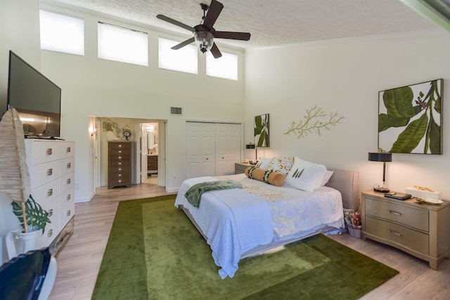 bedroom featuring light wood-type flooring, ceiling fan, a closet, ornamental molding, and a textured ceiling