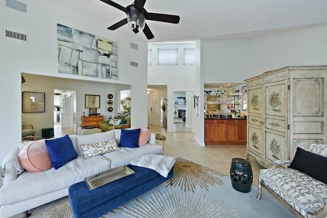 living room featuring a high ceiling, light tile patterned floors, and ceiling fan