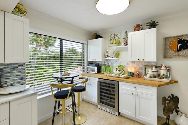 kitchen with tasteful backsplash, wooden counters, wine cooler, and white cabinets