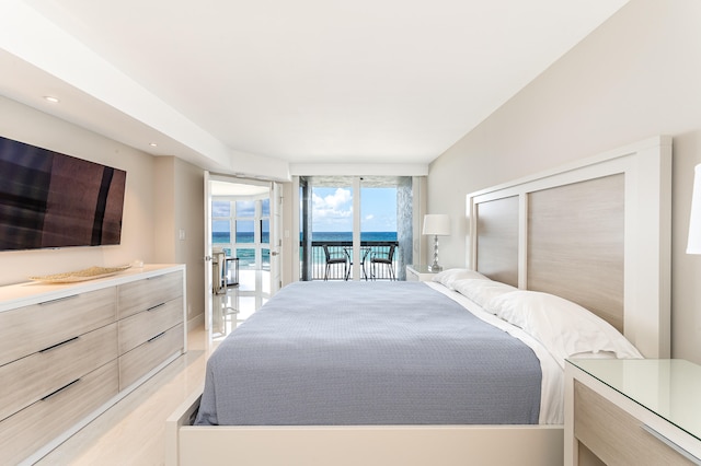 bedroom featuring a water view, floor to ceiling windows, and access to exterior