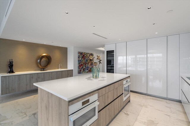 kitchen with white oven, a center island, oven, and white cabinets