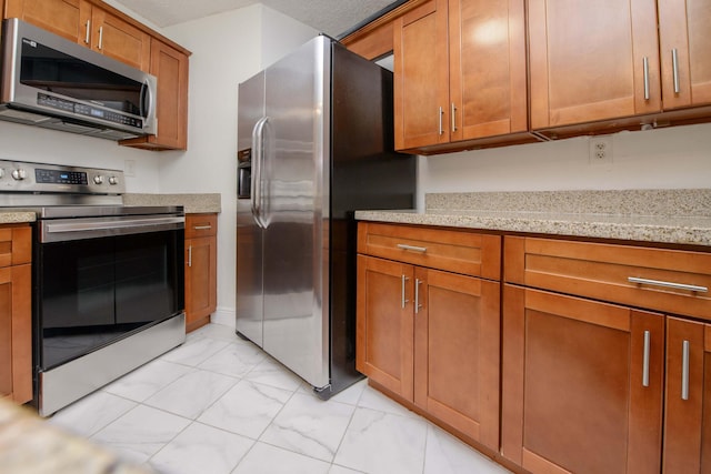 kitchen featuring a textured ceiling, light stone counters, and stainless steel appliances