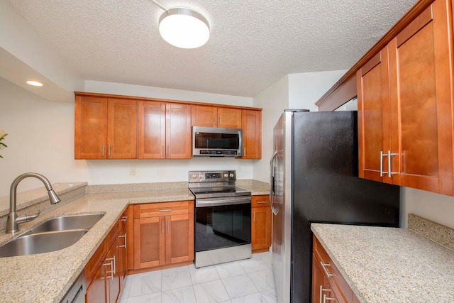 kitchen featuring light stone countertops, a textured ceiling, stainless steel appliances, and sink