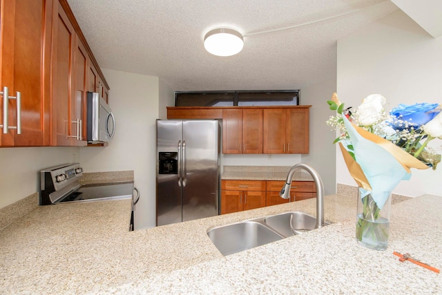 kitchen with sink, light stone countertops, a textured ceiling, kitchen peninsula, and stainless steel appliances