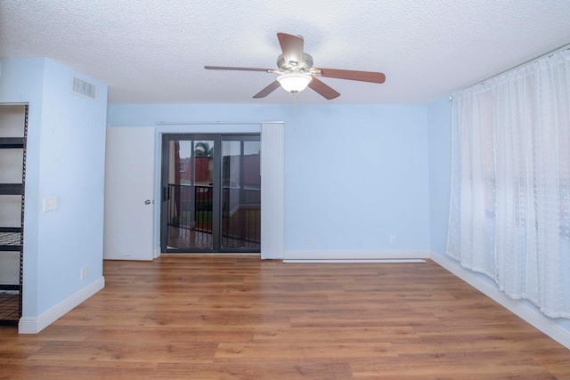 unfurnished room featuring hardwood / wood-style flooring, ceiling fan, and a textured ceiling