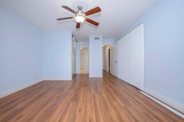 empty room with a textured ceiling, hardwood / wood-style flooring, and ceiling fan