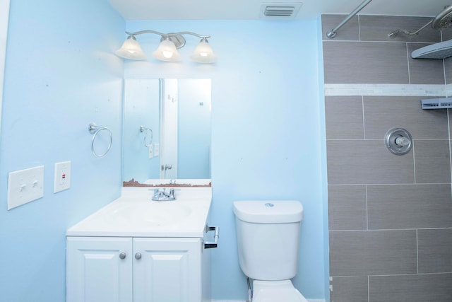 bathroom with vanity, toilet, and a tile shower