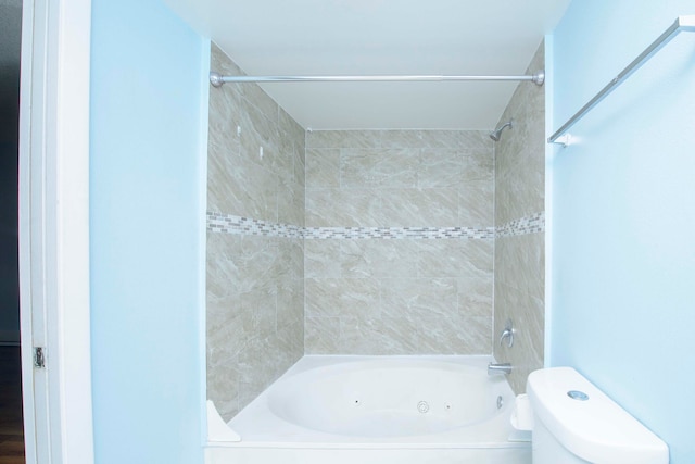 bathroom featuring toilet and tiled shower / bath