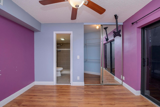 unfurnished bedroom featuring ceiling fan, light wood-type flooring, and a textured ceiling