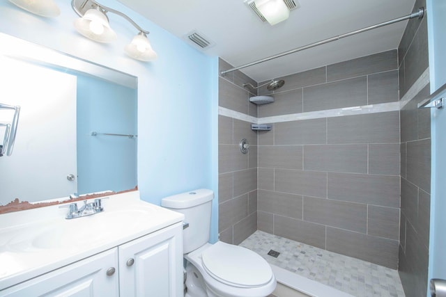 bathroom with tiled shower, vanity, and toilet