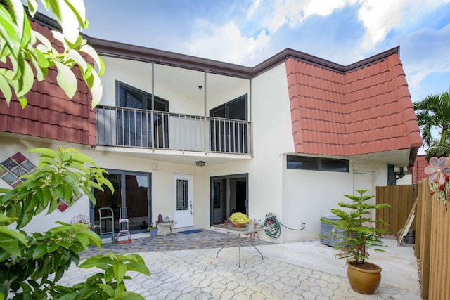 back of property with a balcony and a patio