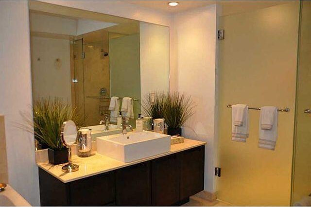 bathroom featuring a shower with door and vanity