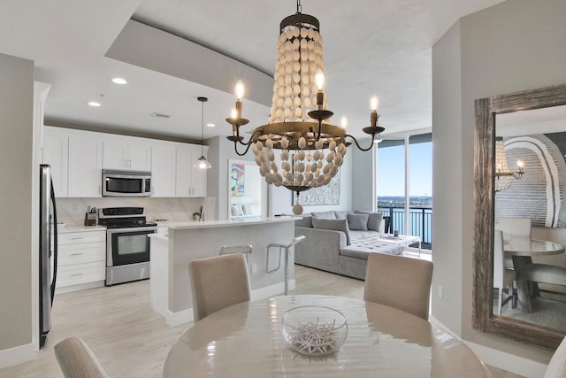 dining room featuring light hardwood / wood-style floors, a water view, and a notable chandelier