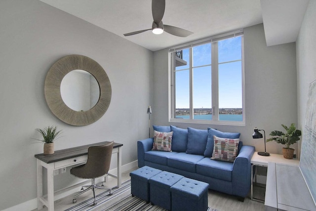 living room featuring ceiling fan, light hardwood / wood-style floors, and a water view