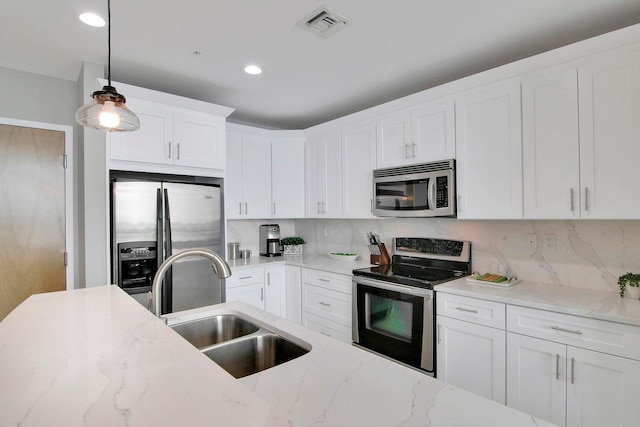 kitchen featuring light stone counters, pendant lighting, backsplash, white cabinetry, and appliances with stainless steel finishes