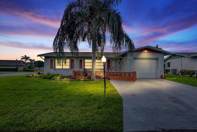 ranch-style house featuring a lawn, central AC, and a garage