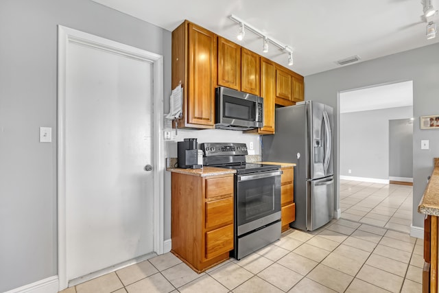 kitchen featuring stainless steel appliances, track lighting, and light tile patterned floors