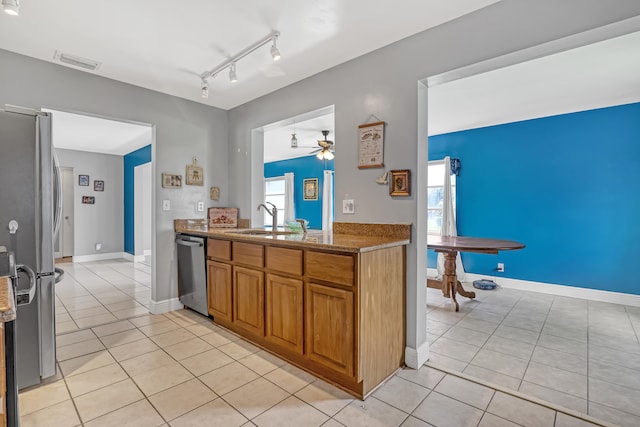 kitchen featuring appliances with stainless steel finishes, rail lighting, light tile patterned floors, ceiling fan, and sink