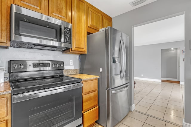 kitchen featuring light tile patterned floors, stainless steel appliances, and light stone counters