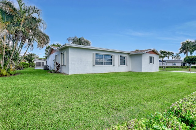 view of front of home with central AC unit and a front yard