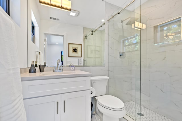 bathroom featuring a shower with door, vanity, and toilet